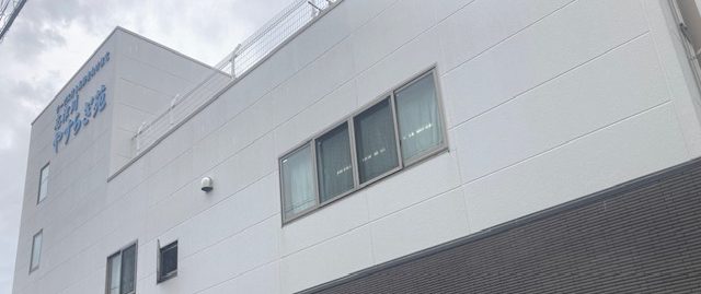 白色のモダン建築の介護施設外観。施設名が左上に表示されている。